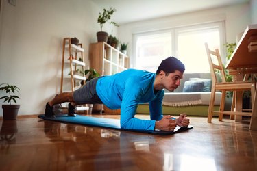 Home workout, young man doing plank in his apartment