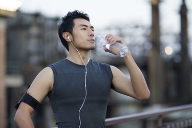 person taking a break to drink a bottle of water during workout