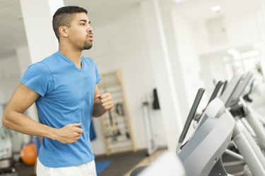 Person in blue T-shirt running on a treadmill.