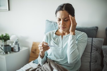 woman at home with a fever, as a side effect of the COVID vaccine