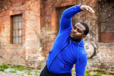 Man in blue jacket stretching outdoor