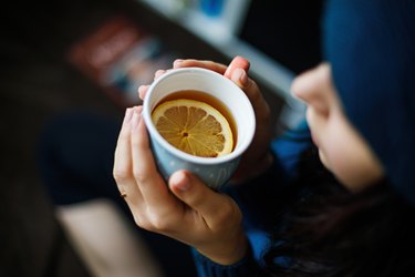 Girl drinking blood test fasting tea with lemon from a mug