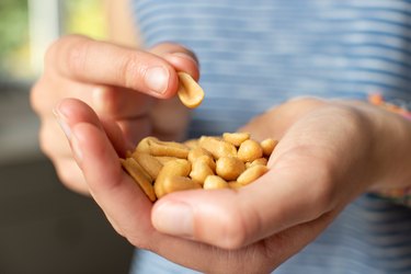 a close up of a person holding a handful of peanuts experiencing digestive issues