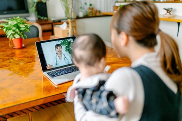 Mother with her baby video calling doctor from home