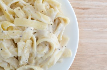 Plate of fettuccine alfredo on wood table top close view