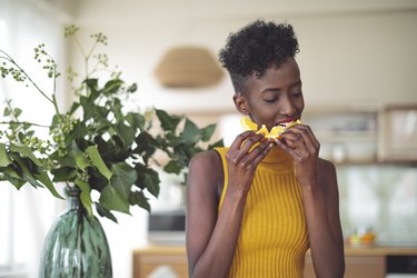 Woman eating orange in office with plant