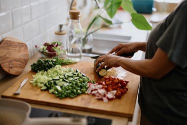 a close up of a person cutting zucchini on a wooden cutting board in their kitchen