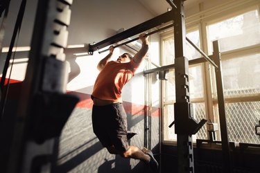 Man doing kipping pull-up in gym