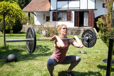 A young woman doing a front squat in her back yard