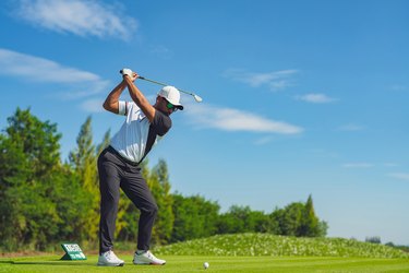Asian man golfing on the course in summer
