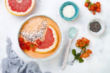 Healthy breakfast set. Superfoods smoothie bowl with chia seeds, coconut, grapefruit and quince flowers. Overhead, top view, flat lay