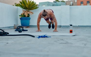 Person doing burpees on exercise mat outside
