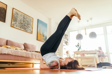 Mature woman doing yoga at home, as a way to treat scoliosis naturally