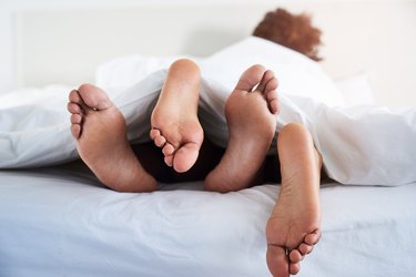 close view of a couple's feet in bed