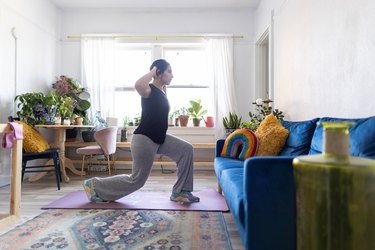 Adult performing split squat test on pink yoga mat in living room