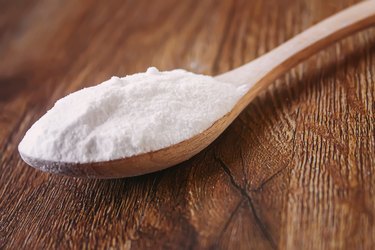 Spoonful of baking soda on a wooden background as a natural fat lip remedy