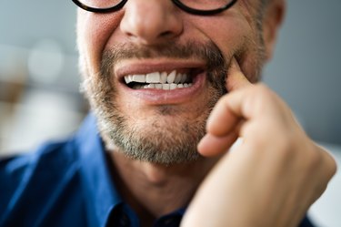 close view of a man holding his jaw after waking up with jaw pain