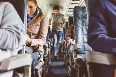 People traveling by airplane with one person walking down the aisle as an airplane exercise to prevent blood clots
