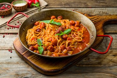 Spaghetti with sausage in tomato sauce on old wooden table