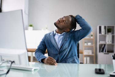man stretching his neck at his office desk