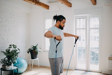 Home workout routine. Black man doing resistance band workout