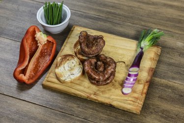 Cow bowels (chitterlings) presented on a wooden board with ingredients, ready to grill