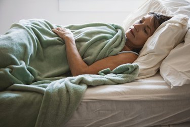 Woman lying in bed and thinking about sleeping, as a natural remedy for insomnia