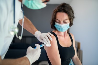 Woman with face mask getting vaccinated against covid-19 variants
