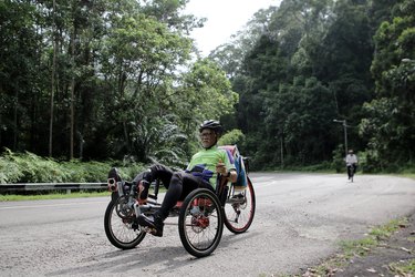 older adult rides a recumbent bike in nature for its many fitness benefits