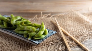 蒸和煮熟的冷冻绿色毛豆大豆在盘子里。