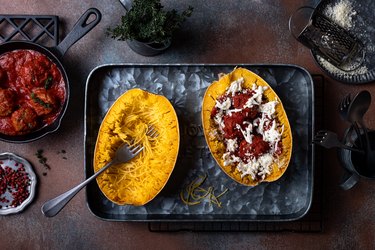 Cooked stuffed Spaghetti squash with meatballs in tomato sauce on a roasting pan