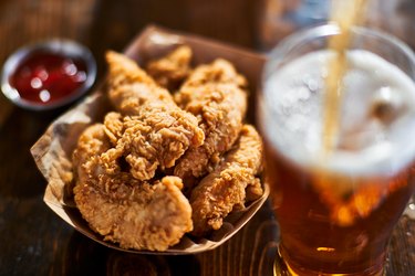 focus on fried chicken tenders in basket with beer