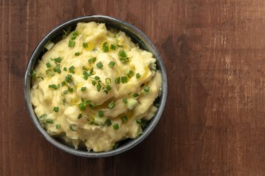 Pomme puree, mashed potatoes with scallions and thyme, shot from the top on a dark rustic background with a place for text