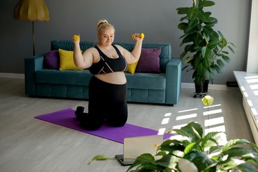 Home fitness classes and Pilates workouts , online classes at home . An overweight woman exercises under the supervision of a personal trainer.