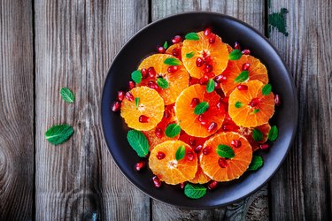 Raw fresh Citrus Salad with Oranges, pomegranate and mint on wooden background