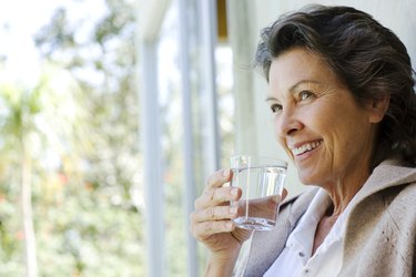 Woman with glass of water standing in doorway