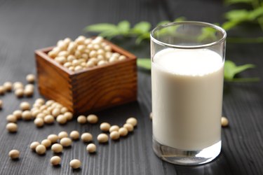 Vitamin B12-rich fortified soy milk next to soybeans on table.