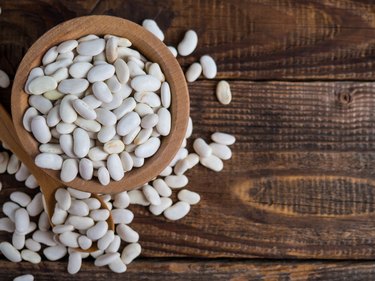 white beans, one of the foods high in vitamin C and zinc,  in a wooden bowl on an old wooden table, legumes,