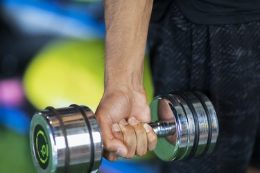 Close up of a hand holding a dumbbell while doing wrist strengthening exercises to increase wrist size