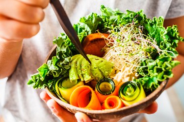 Healthy vegan lunch in a coconut bowl. A child eating Buddha bowl.