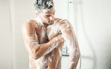 Person taking a shower using soap for body odor.
