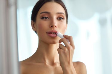 A woman applying lip balm made of beeswax for face