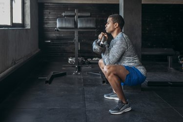 Man doing a kettlebell squat during a 20-minute HIIT workout