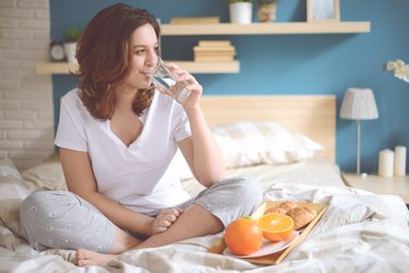 Woman in the bedroom drinking water for constipation