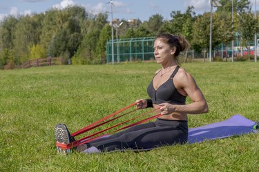 woman does seated row exercise to keep shoulder blades down and together outdoor