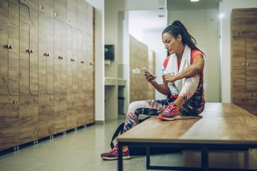 Athlete using cell phone at gym's dressing room.