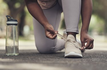 Shot of a woman tying her shoes before working out