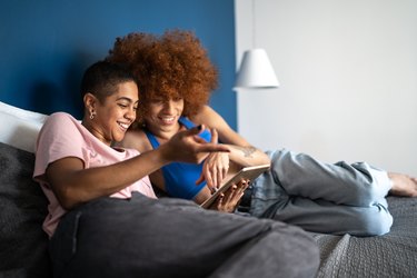 Happy couple using digital tablet in bed at home