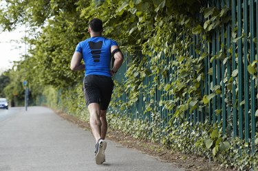 Back view of person running on a paved path outside.