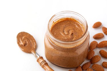 Small jar of fresh almond butter with raw almonds